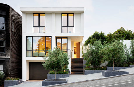 A modern, two-story home with sleek, white exterior, expansive windows, and a welcoming entrance.