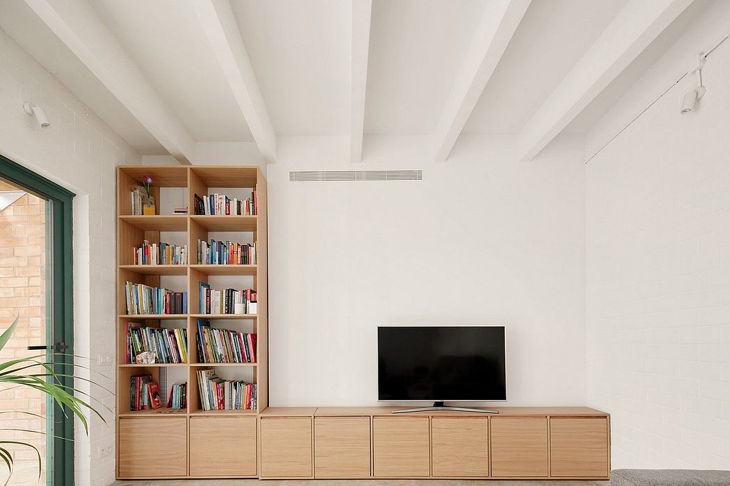 Minimalist living room with built-in wood shelving and TV unit, concrete floor.