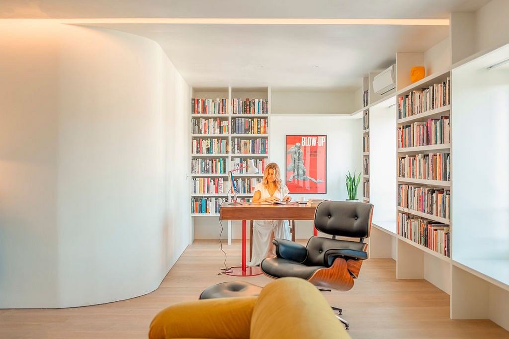 Bright, modern home office with built-in bookshelves, comfortable seating, and artwork.