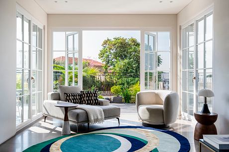 Bright living room with floor-to-ceiling windows, modern furniture, and vibrant garden view.