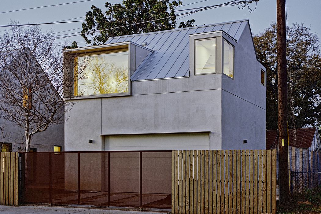 A modern, two-story residence with a striking angular roof, large windows, and a wooden fence.