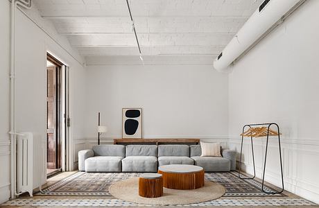 Spacious modern living room with concrete ceiling, patterned tile floor, and minimalist furnishings.