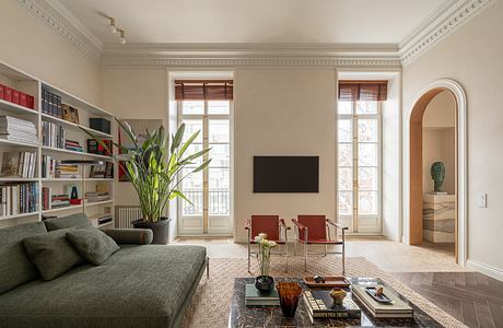 Elegant living room with ornate crown molding, large windows, and eclectic furnishings.