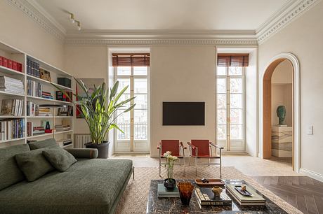 Elegant living room with ornate crown molding, large windows, and eclectic furnishings.