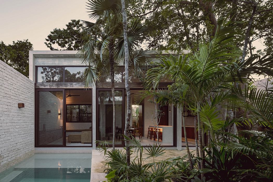 Modern tropical villa with glass walls, pool, and lush palm tree garden.