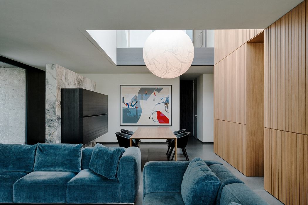 Sleek, modern interior with plush teal sofa, abstract artwork, and large globe light.