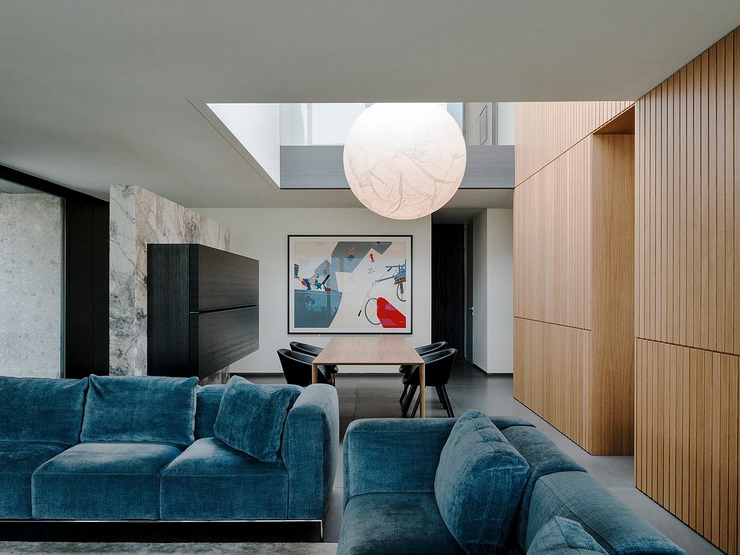 Sleek, modern interior with plush teal sofa, abstract artwork, and large globe light.