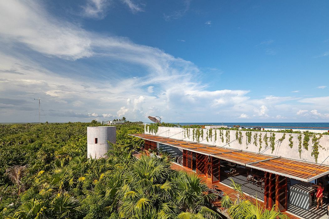 A tropical resort with a wooden boardwalk, surrounded by lush greenery and overlooking the sea.