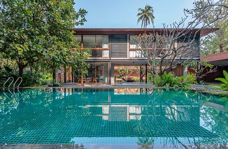 A contemporary tropical house with a large swimming pool reflecting the building.