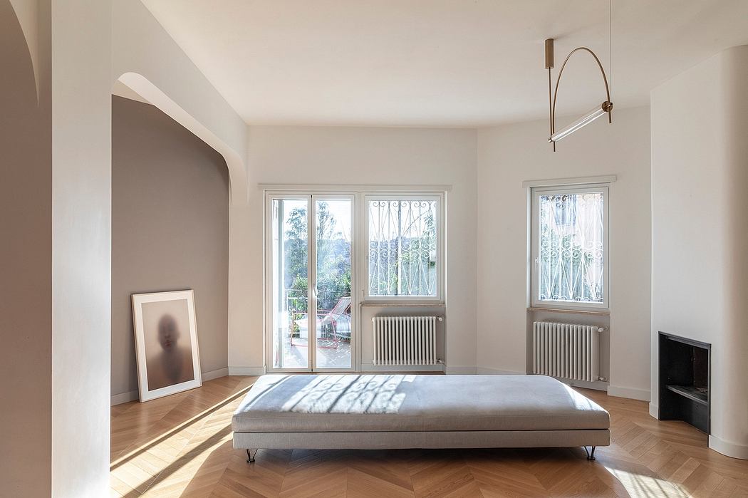 Spacious and bright bedroom with large windows, hardwood floors, and modern lighting.