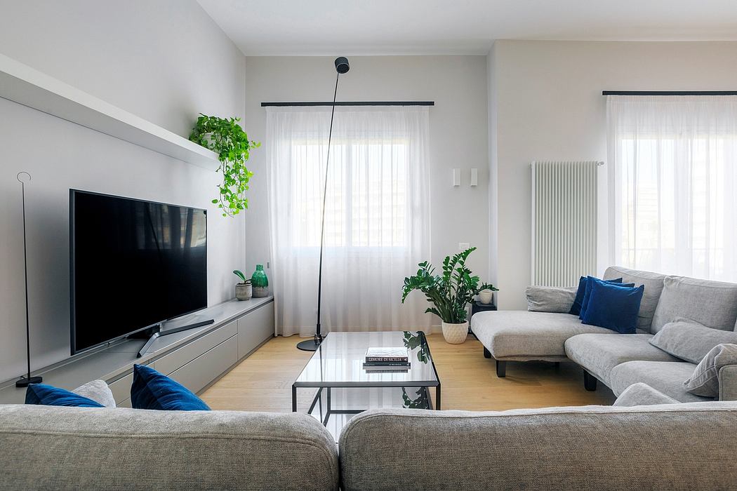 Modern living room with glass coffee table, TV stand, and potted plants adding natural accents.