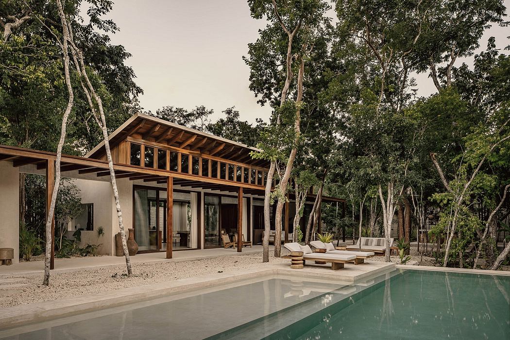 A modern wooden-framed home with a pool and lounge area surrounded by lush greenery.