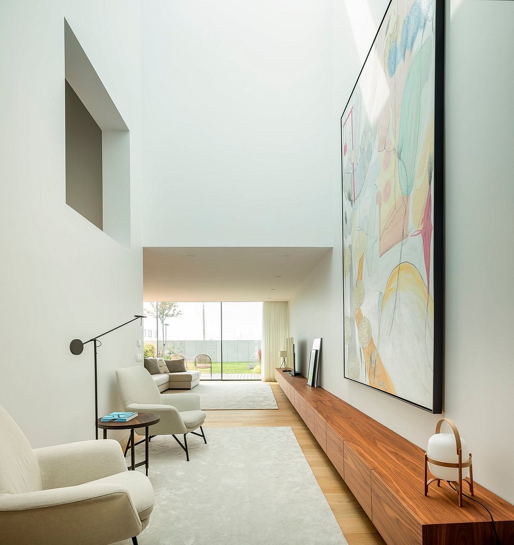 A modern and minimalist living room with a large abstract artwork, wooden furniture, and a view to the exterior.