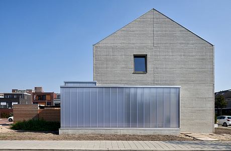 A modern, minimalist architectural design featuring a gray wooden exterior and large glass windows.