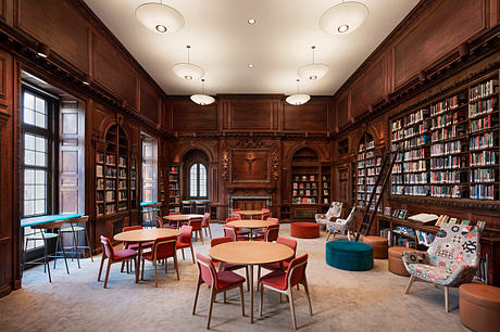 Ornate wood-paneled library with modern furnishings and bookshelves covering the walls.