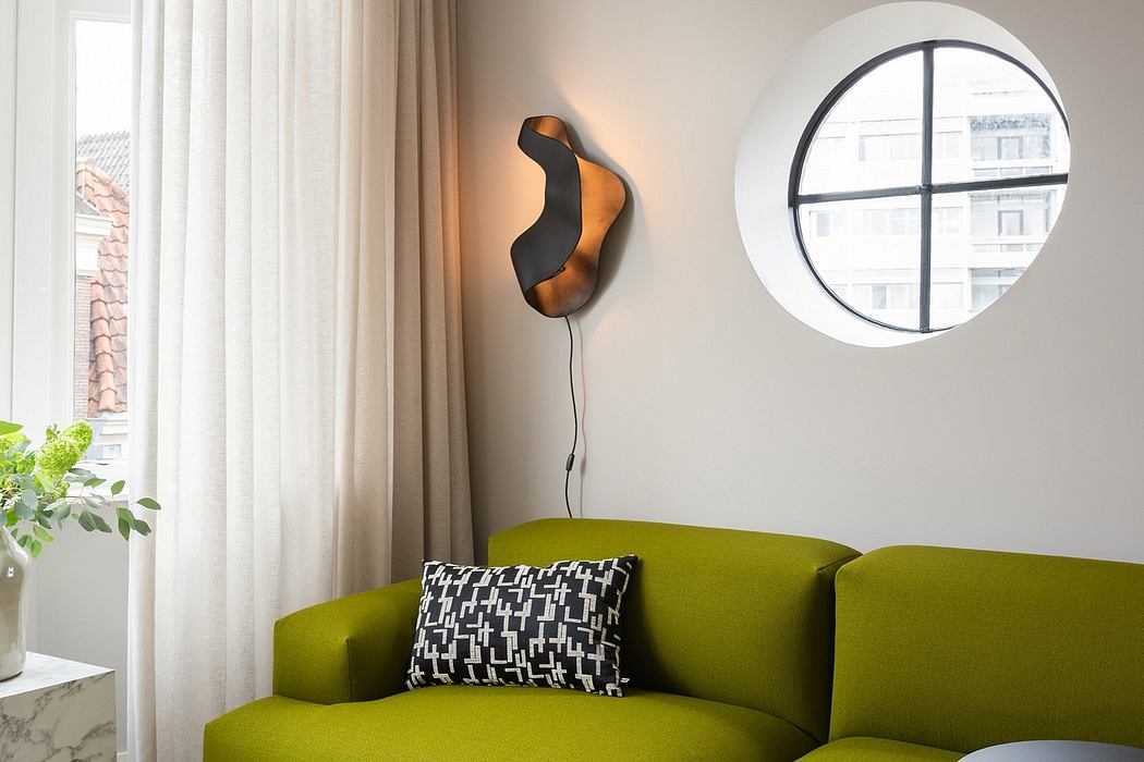 Modern living room with green sofa, round window, and abstract wall sconce.