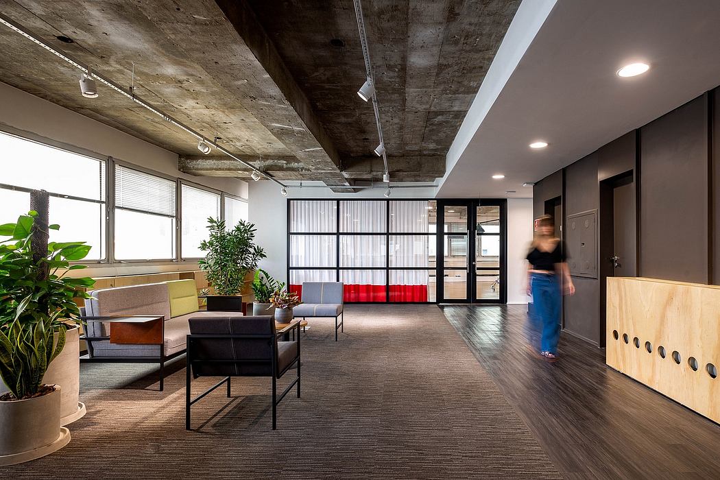 A contemporary office space with exposed concrete ceiling, plants, and modern furniture.