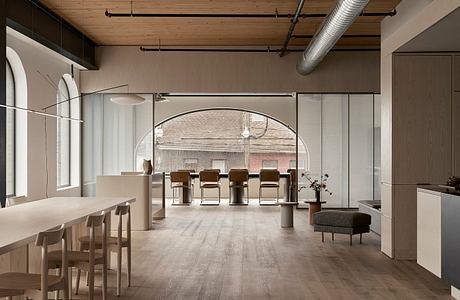 Minimalist interior with wooden beams, arched windows, and contemporary furniture.