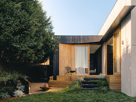 Modern cabin-style home with wooden siding, covered porch, and lush landscaping.