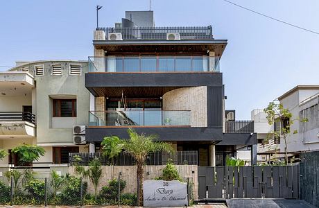 Modern multi-story residence with glass walls, wooden accents, and tropical landscaping.