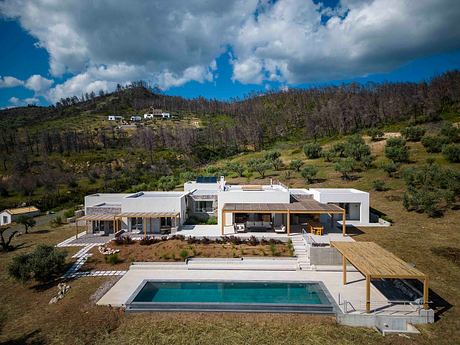 A modern, open-concept home nestled in a lush, mountainous landscape with a private pool.