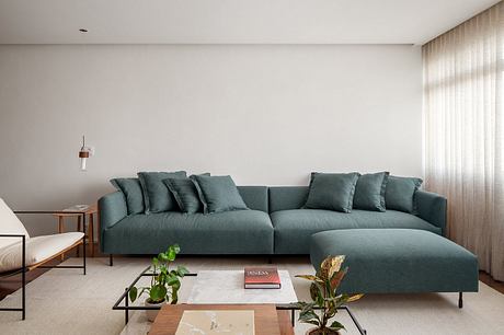 Minimalist living room with a large, comfortable green sofa and a marble coffee table.