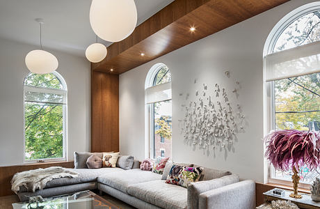 Spacious living room with wood-paneled walls, arched windows, and pendant lighting.