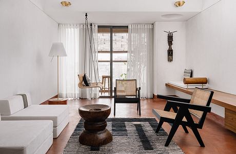 A spacious, minimalist living room with warm wood tones, natural textures, and a cozy seating area.