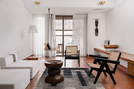 A spacious, minimalist living room with warm wood tones, natural textures, and a cozy seating area.