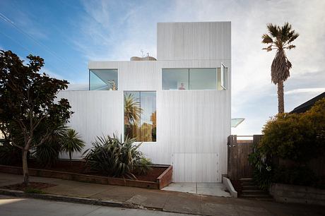 Modern white building with large windows and a palm tree in the foreground.