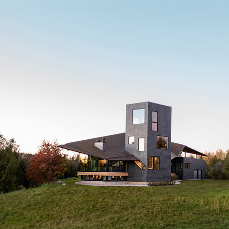 Modern multi-story home with asymmetric brick facade, large windows, and porch overlooking grassy lawn.