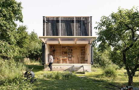 A rustic, wooden cabin-like structure with a bookshelf-lined interior and outdoor space.