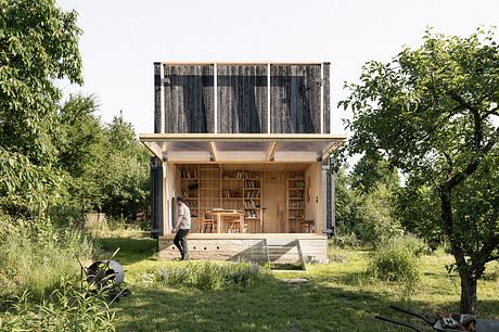 A rustic, wooden cabin-like structure with a bookshelf-lined interior and outdoor space.