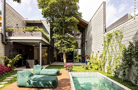 Stunning modern architecture with lush greenery, pool, and cozy outdoor seating.