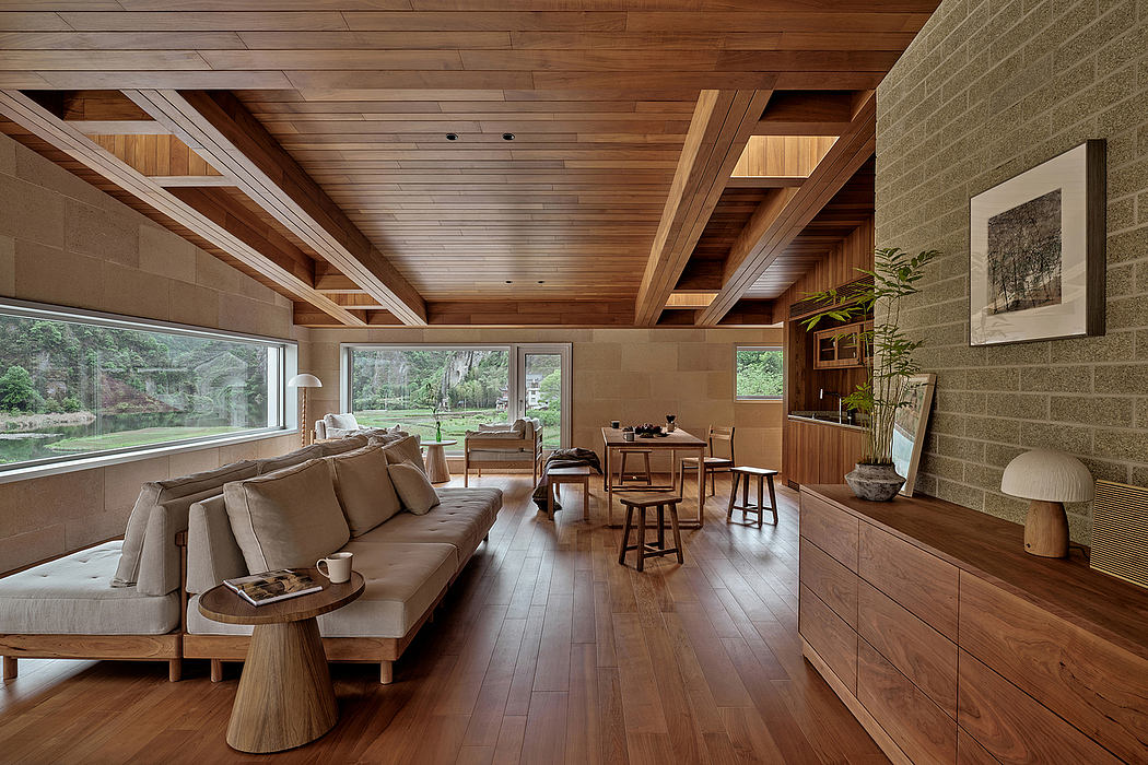 Cozy open-plan living space with wooden beams, large windows, and a minimalist aesthetic.