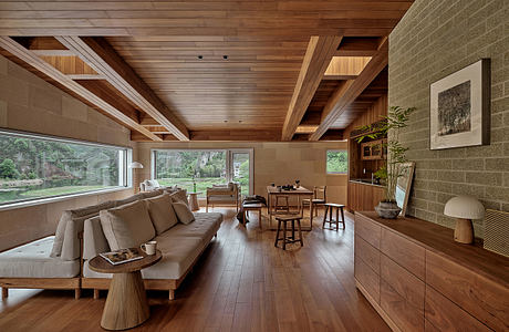 Cozy open-plan living space with wooden beams, large windows, and a minimalist aesthetic.