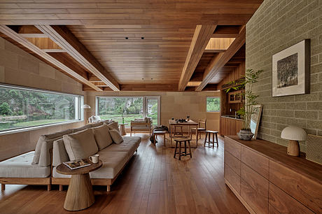 Cozy open-plan living space with wooden beams, large windows, and a minimalist aesthetic.