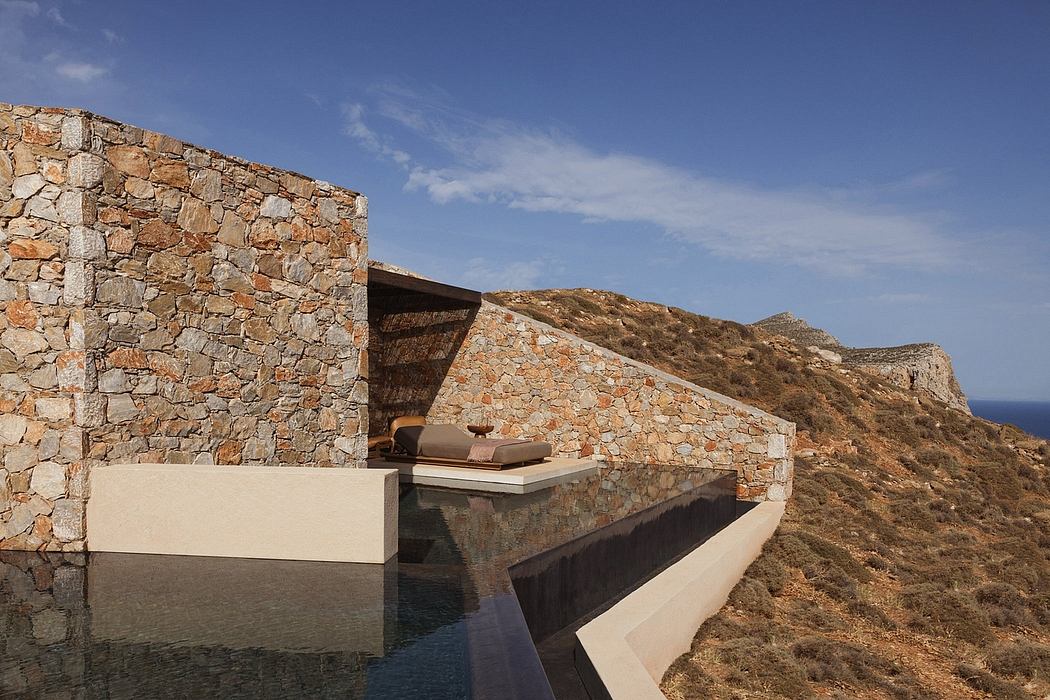 An impressive stone-walled terrace with a water feature set against a rugged hillside.