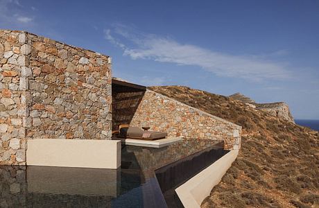 An impressive stone-walled terrace with a water feature set against a rugged hillside.