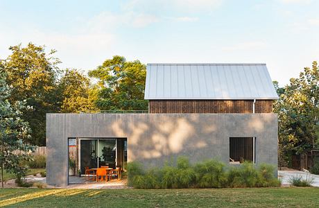 A modern, minimalist structure with a mix of concrete, wood, and large windows overlooking the lush greenery.