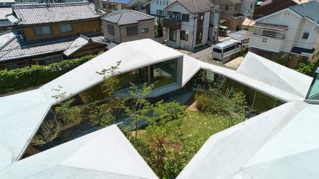 A modern architectural design with a central courtyard and glass walls overlooking a lush garden.