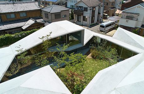 A modern architectural design with a central courtyard and glass walls overlooking a lush garden.