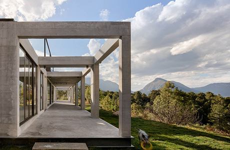 Modern concrete structure with glass walls, framed views of mountain landscape.