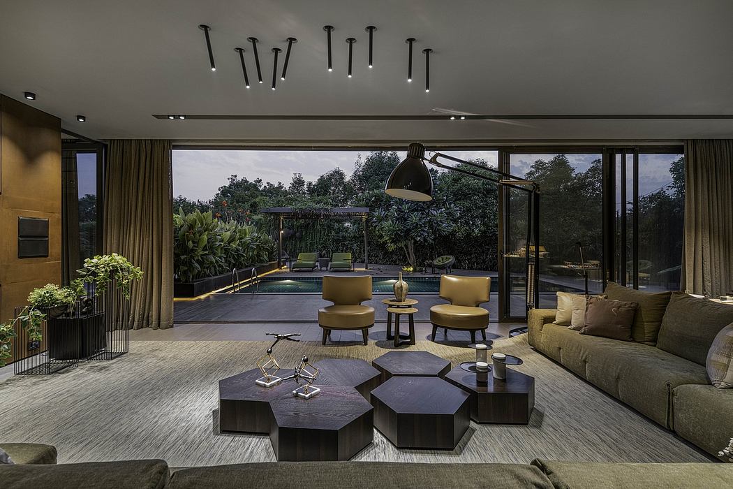 Expansive modern living room with sleek furniture, lush greenery, and large windows overlooking the pool.