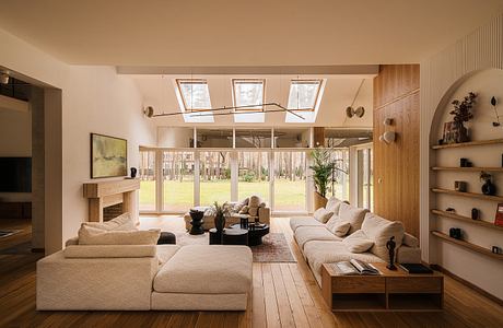 Cozy living room with large windows, wood accents, and a fireplace in a modern country home.