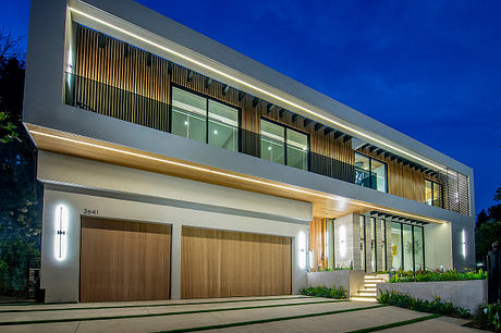 Modern two-story residential building with clean lines, wood accents, and recessed lighting.