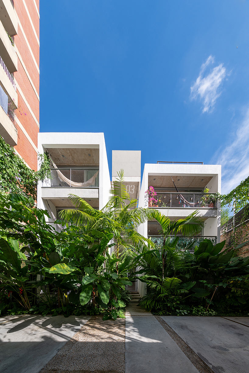 Modern tropical architecture with lush greenery, balconies, and clean lines.