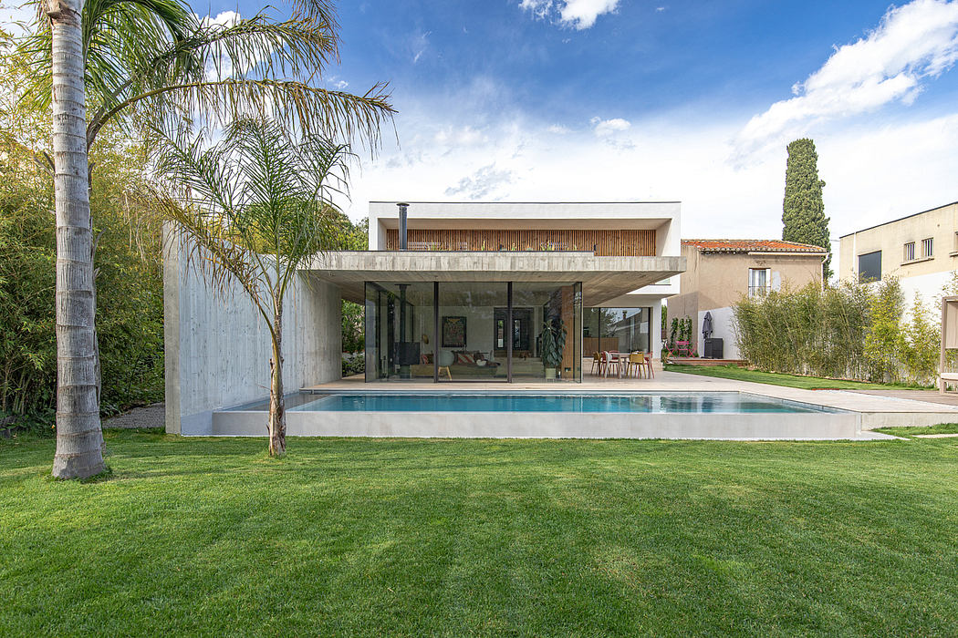 Sleek concrete home with large covered patio, pool, and lush landscaping.