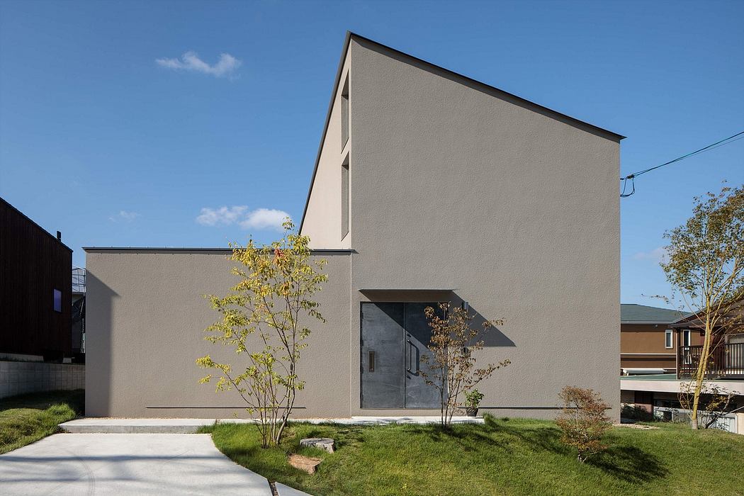 A minimalist, modern gray building with a prominent roofline and large windows.