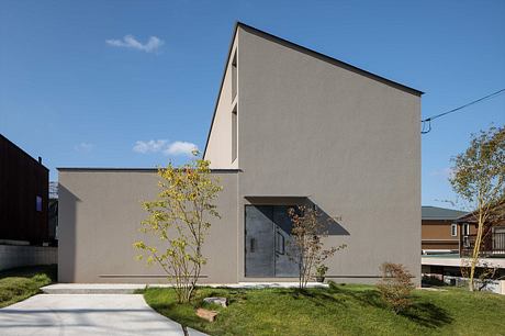 A minimalist, modern gray building with a prominent roofline and large windows.